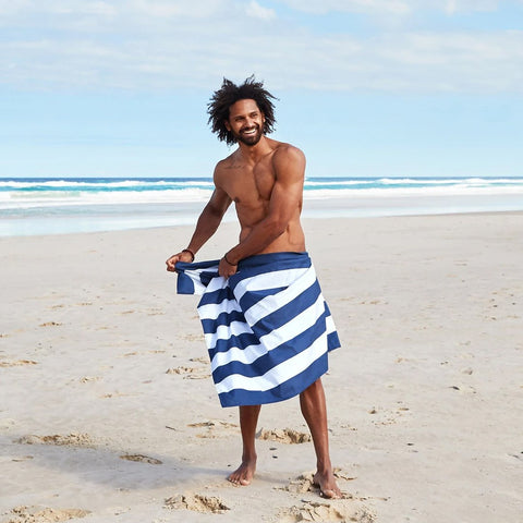 Towels collection image of a man with a striped towel around him at the beach 