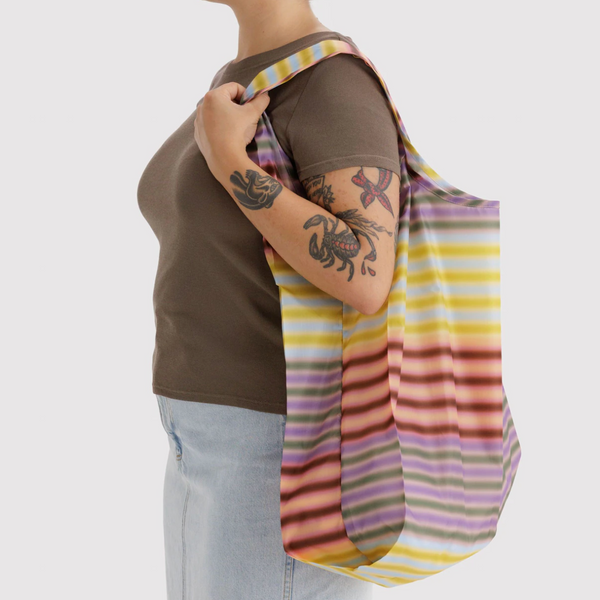 Person holding a colorful striped bag over their shoulder against a white background