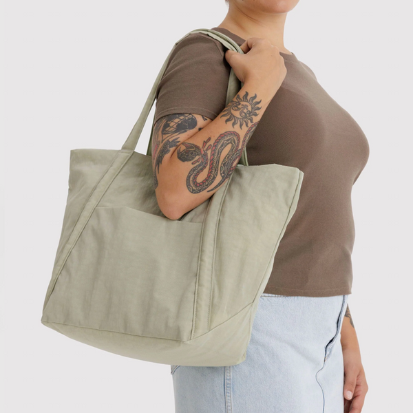 Person holding a beige tote bag against a plain background