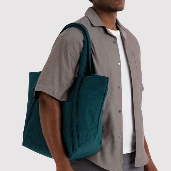 Man carrying a teal tote bag on a plain background